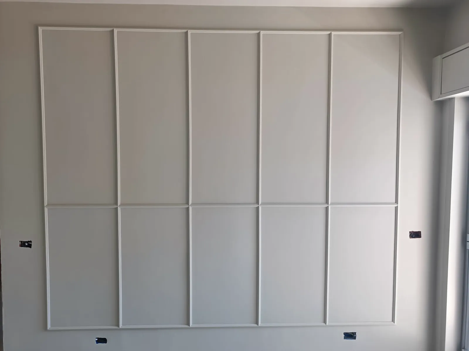 Parete grigia con boiserie a pannelli rettangolari bianchi