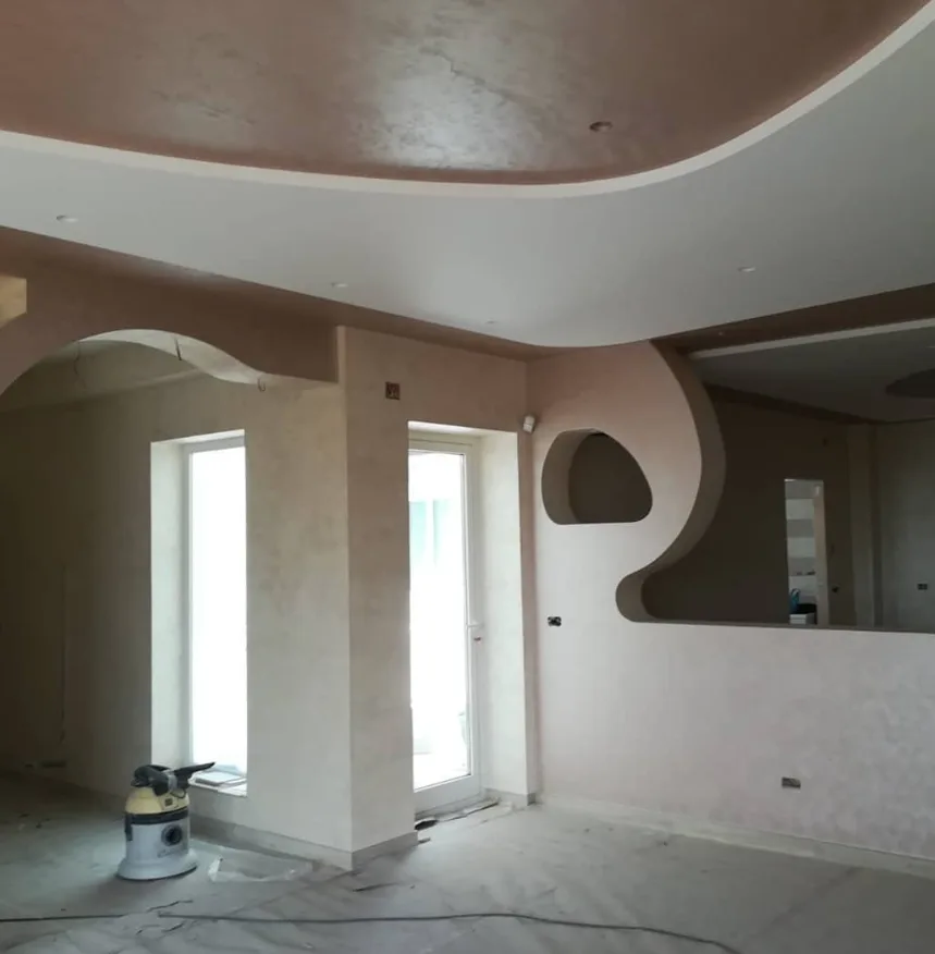 Soggiorno con controsoffitto sagomato e pareti stuccate